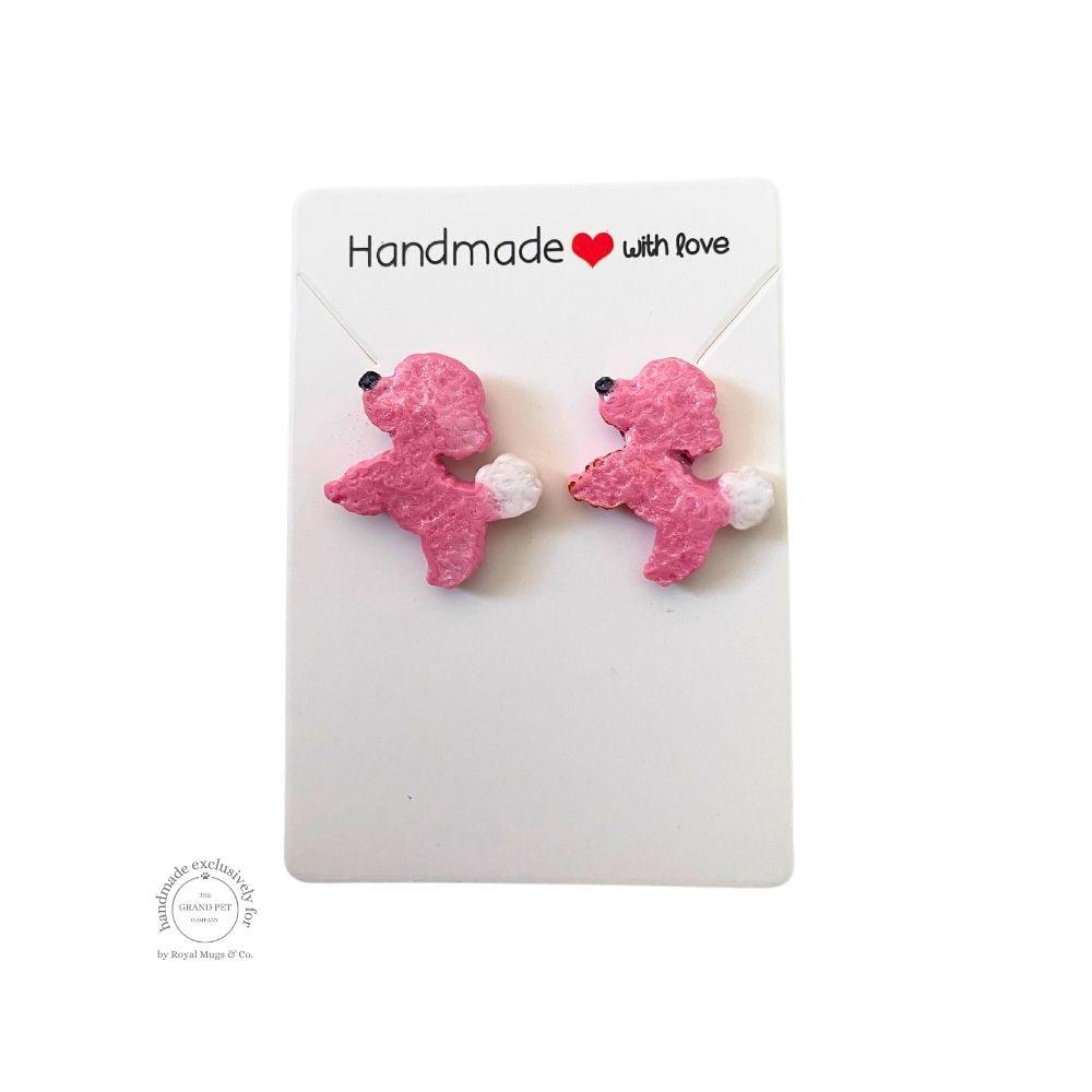 A pair of pink polymer clay stud earrings designed to resemble poodle dogs, displayed on a white backing card with 'Handmade with love' text.