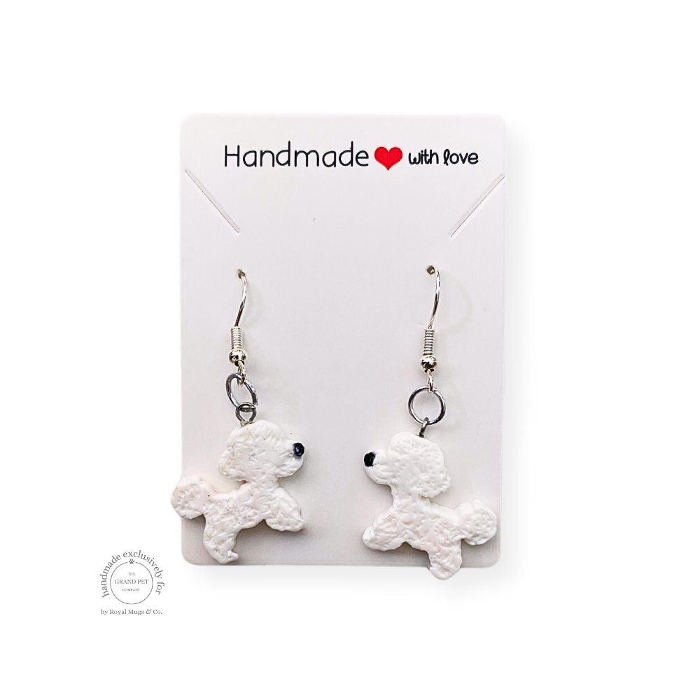 Handcrafted polymer clay earrings in the shape of a white poodle with black noses, presented on a white card with 'HANDMADE with love' text.