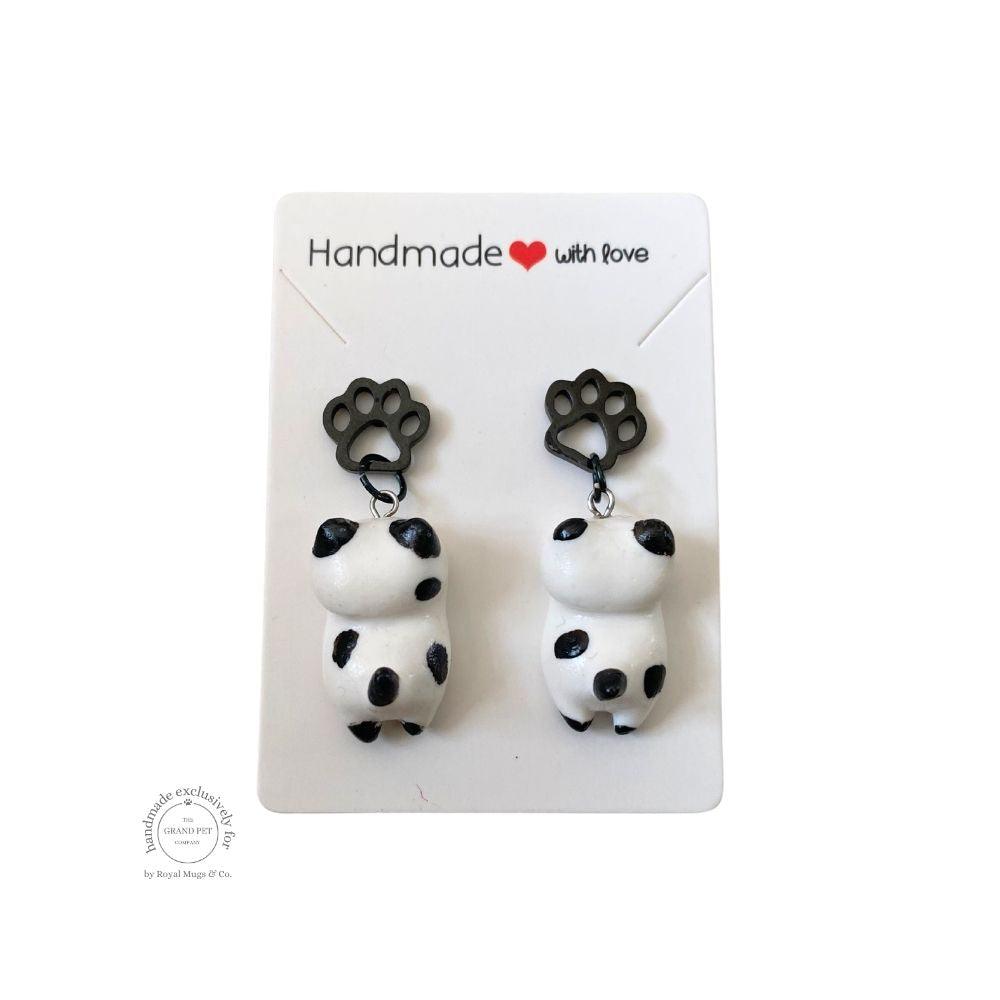 A pair of white and black polka polymer clay earrings in the shape of cats with black pawprint, displayed on a white backing card with 'handmade with love' text.