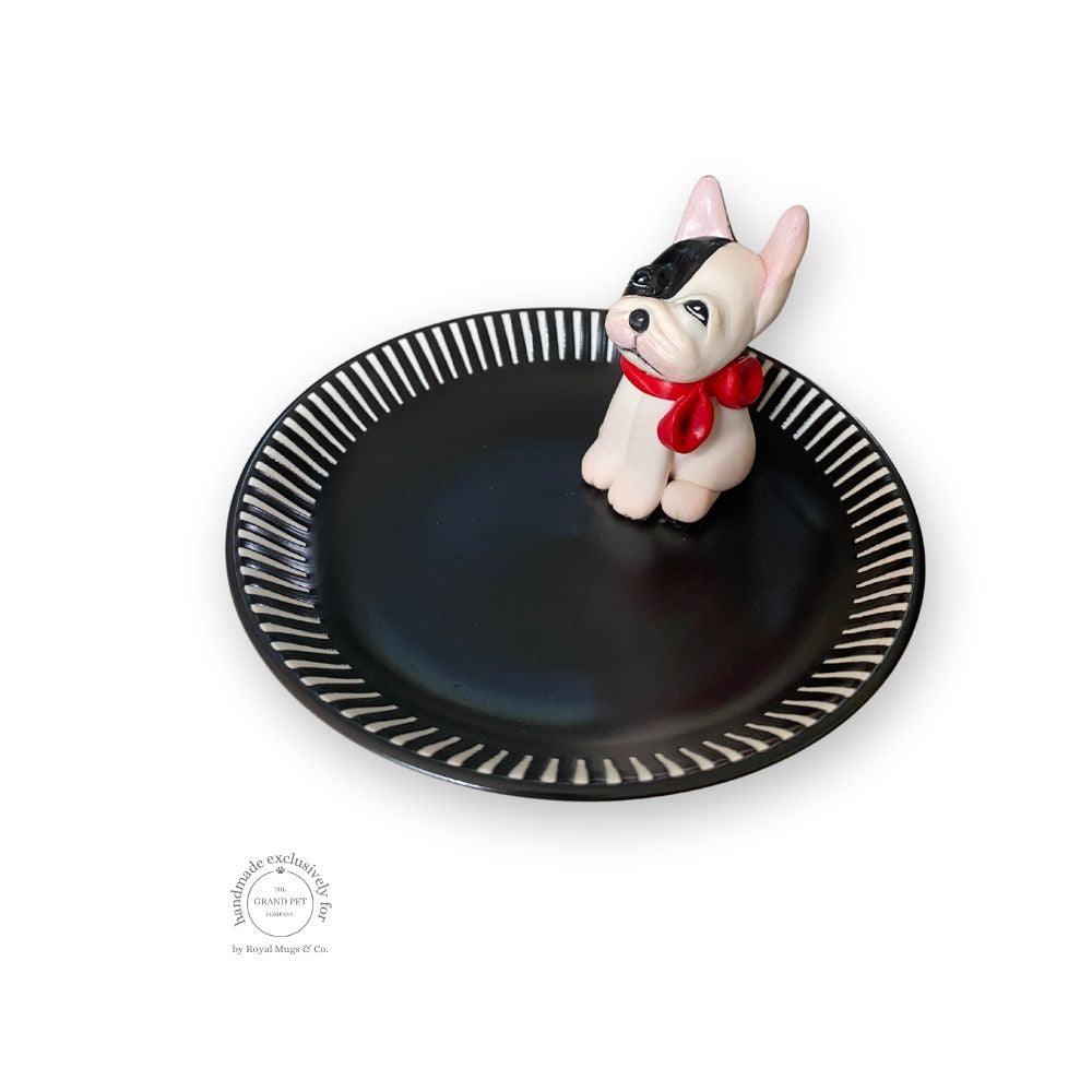 A handmade polymer clay character on a matching ceramic dish.