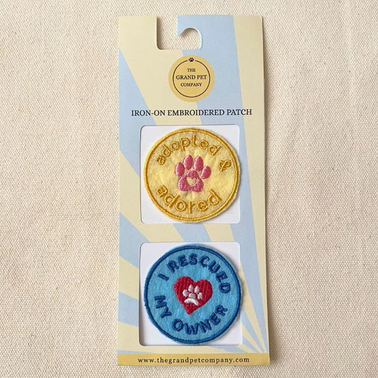 Two blue and yellow rescue themed iron on felt embroidered felt patches on packaging with 'The Grand Pet Company' branding.