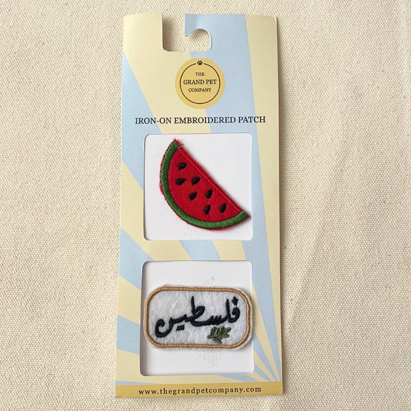 Two iron-on felt embroidered patches with watermelon design and Arabic Palestine text in packaging on a beige background