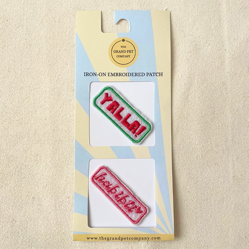 Two colourful iron on embroidered felt patches with sweet Arabic expressions on packaging with 'The Grand Pet Company' branding.